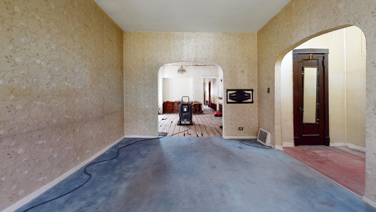 An empty room with a blue carpet and a wooden door