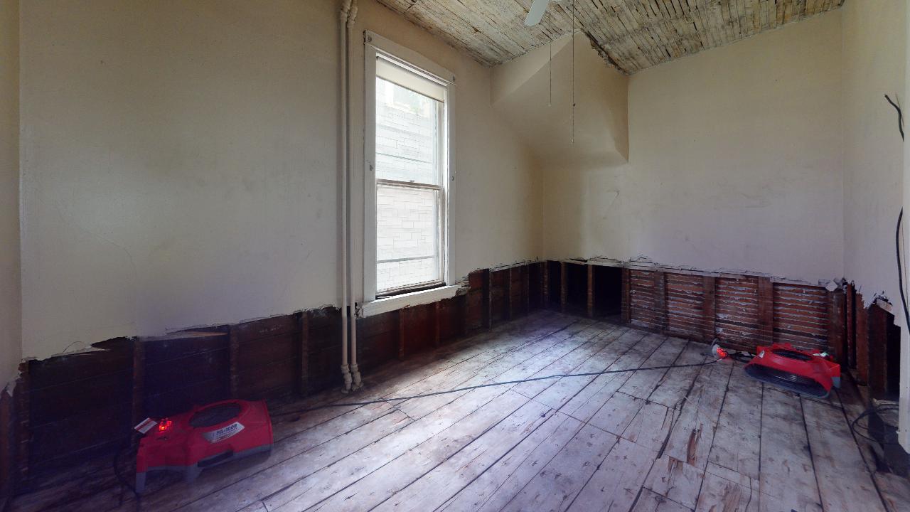 An empty room with a red toy car on the floor.