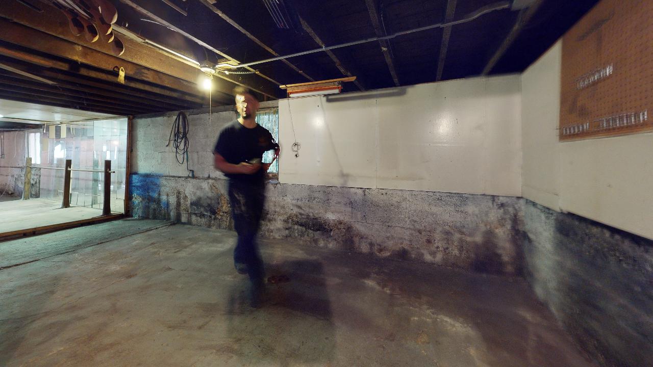 A man is standing in a basement with a camera.