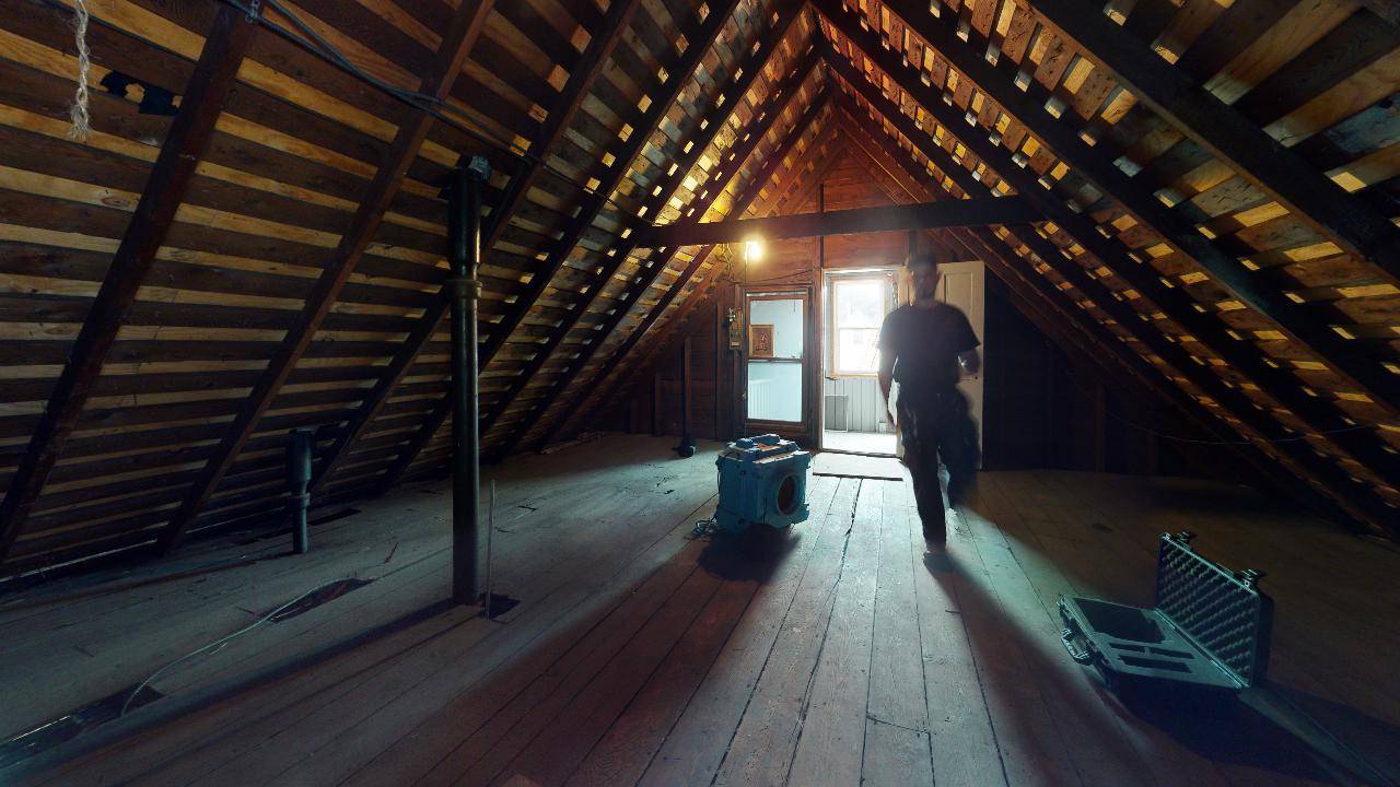 A man is standing in the attic of a house