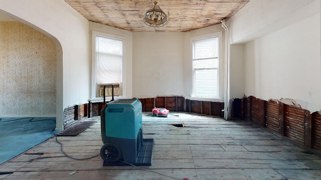 An empty room with a vacuum cleaner in the middle of it.