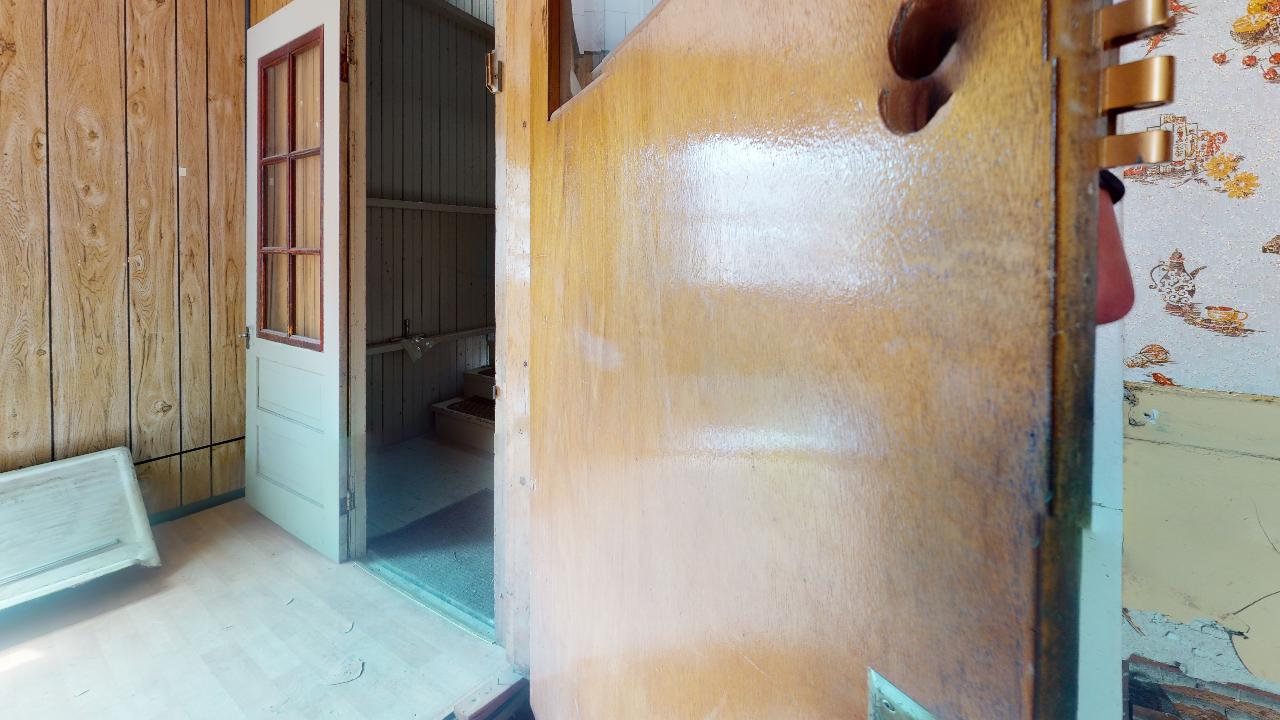 A wooden door is open to a bathroom in a house.