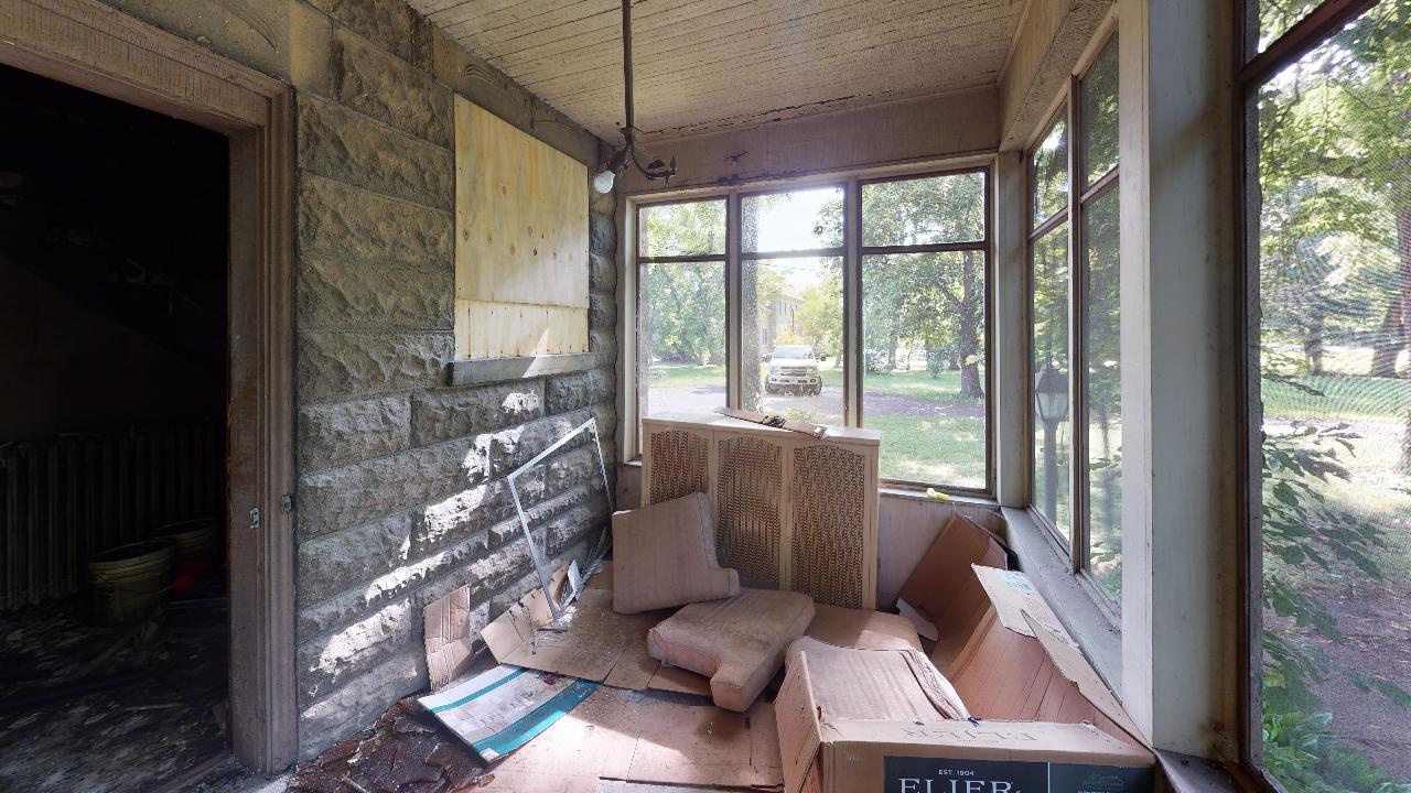A porch with a lot of windows and a box on the floor.