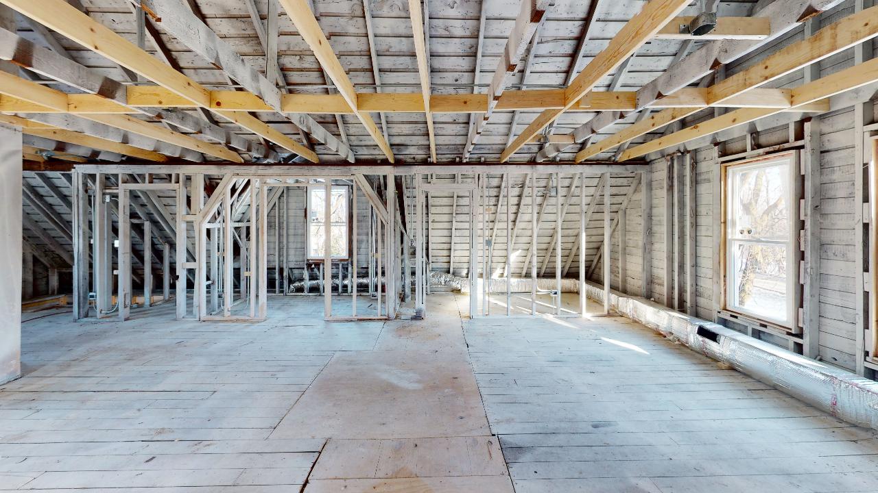 An empty room with wooden beams and a ceiling in a building under construction.