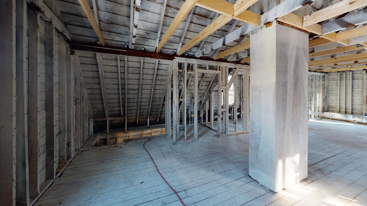 An empty room with a wooden ceiling and a pillar in the middle of it.