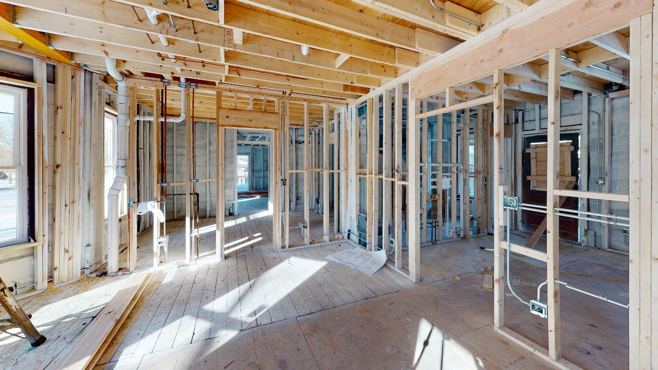 A room in a house under construction with wooden beams and windows.