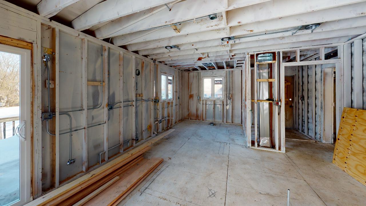A room in a house under construction with wooden walls and a ceiling.