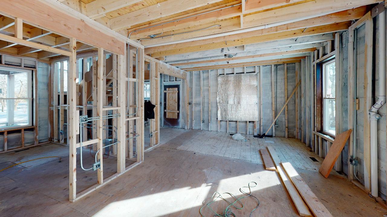 A room in a house under construction with wooden walls and windows.