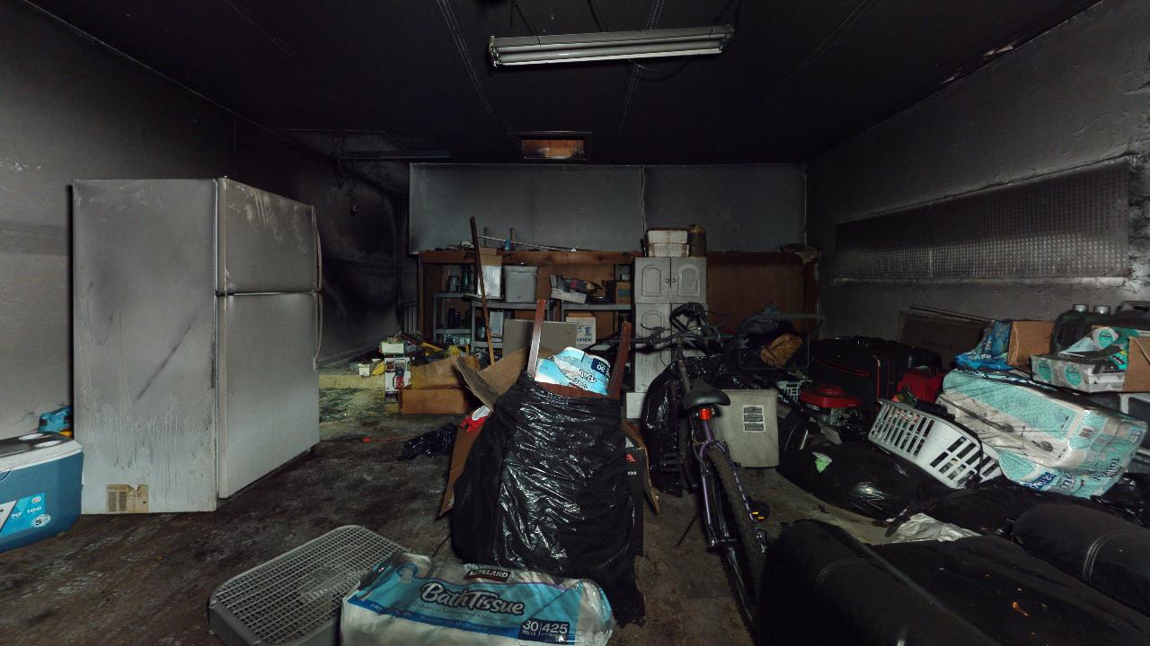 A garage filled with lots of junk and a refrigerator.