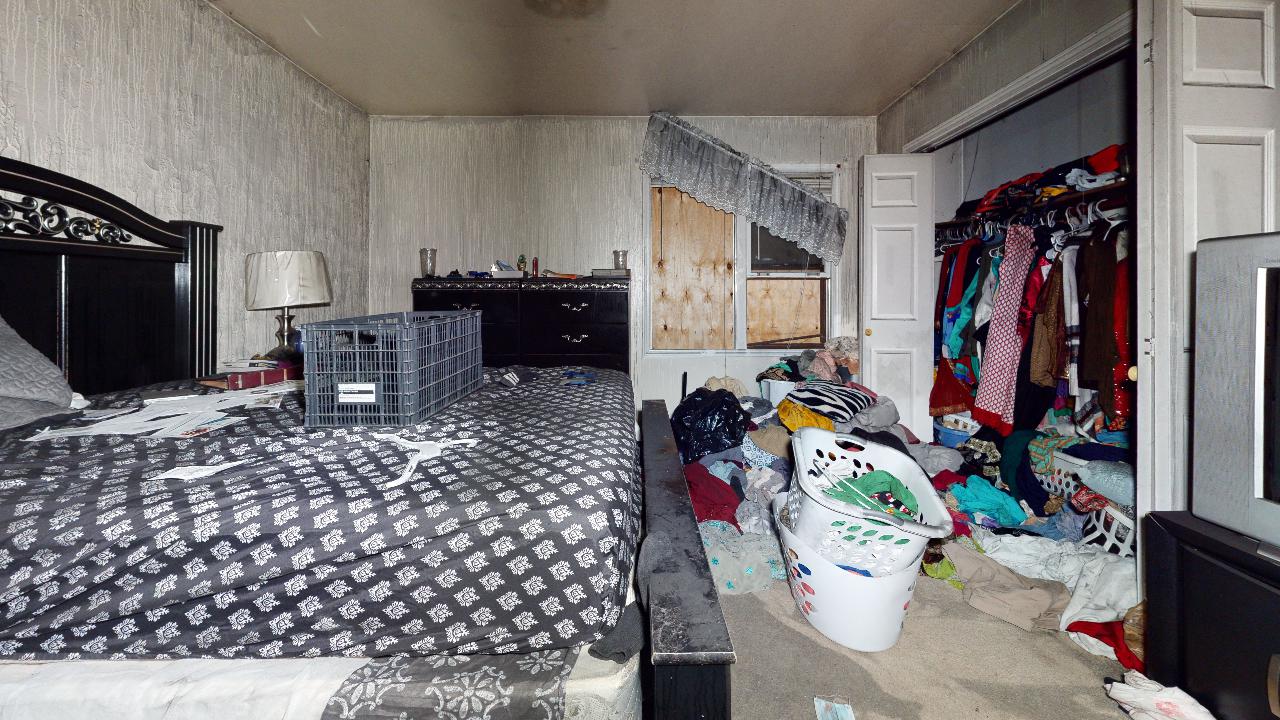 A bedroom with two beds and a closet filled with clothes.