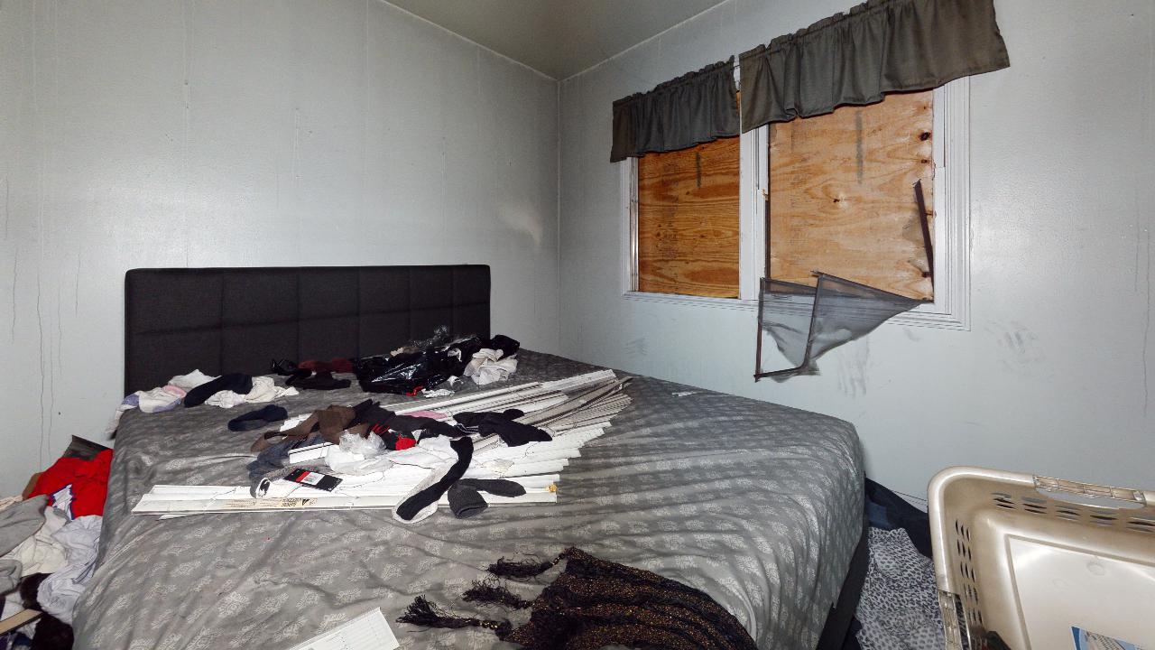 There is a bed in the middle of a room with a window.