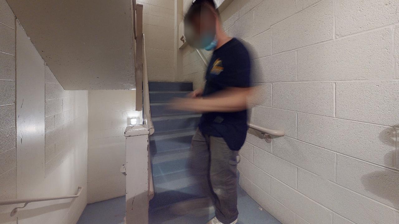 A man wearing a mask is walking down a set of stairs.