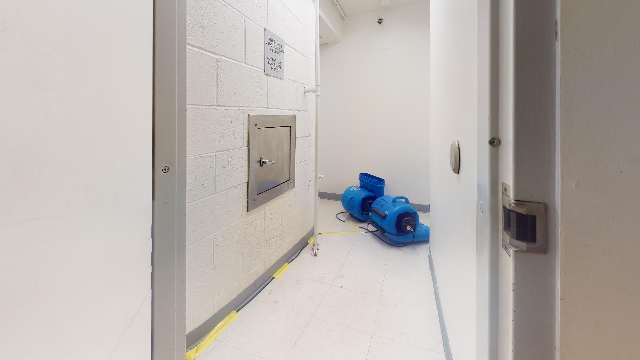 A hallway with a door and a blue bag on the floor.