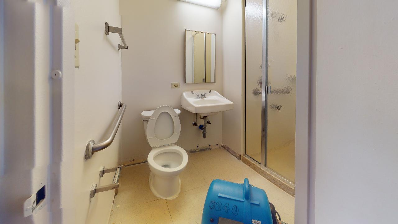 A bathroom with a toilet , sink and shower.