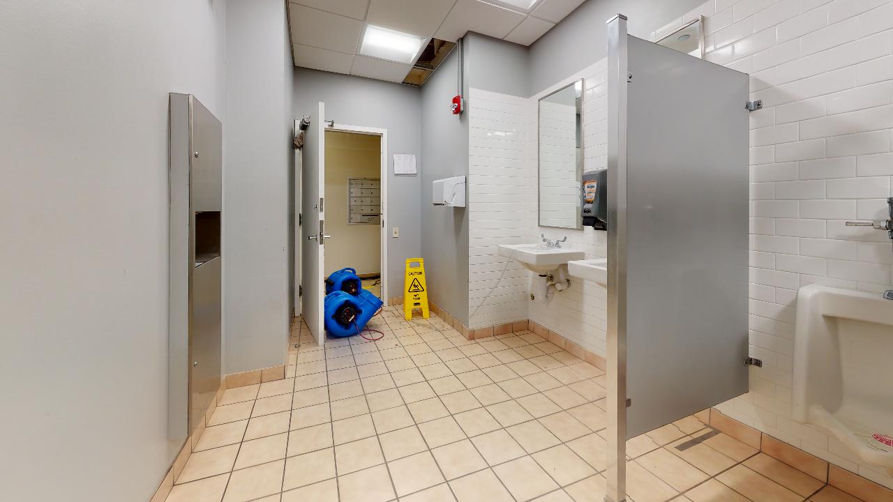 A bathroom with a yellow caution sign on the floor.