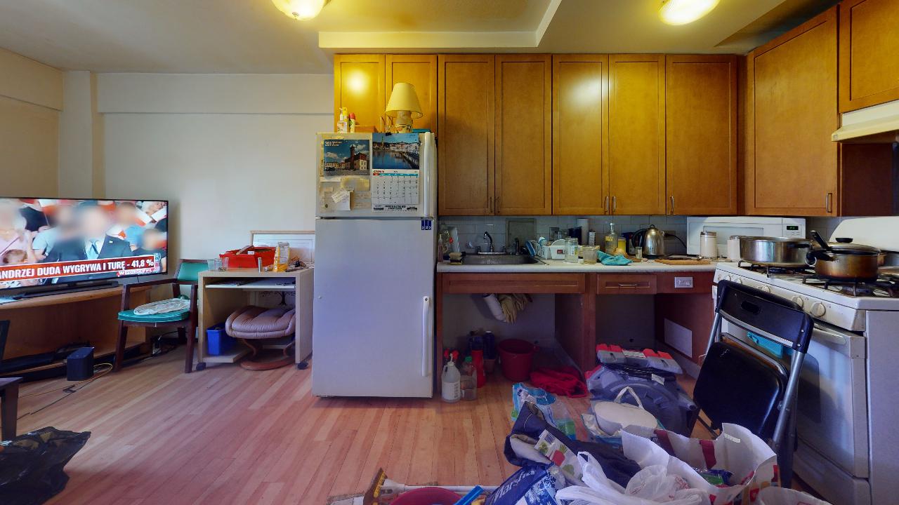 A kitchen with a refrigerator , stove , sink and television.