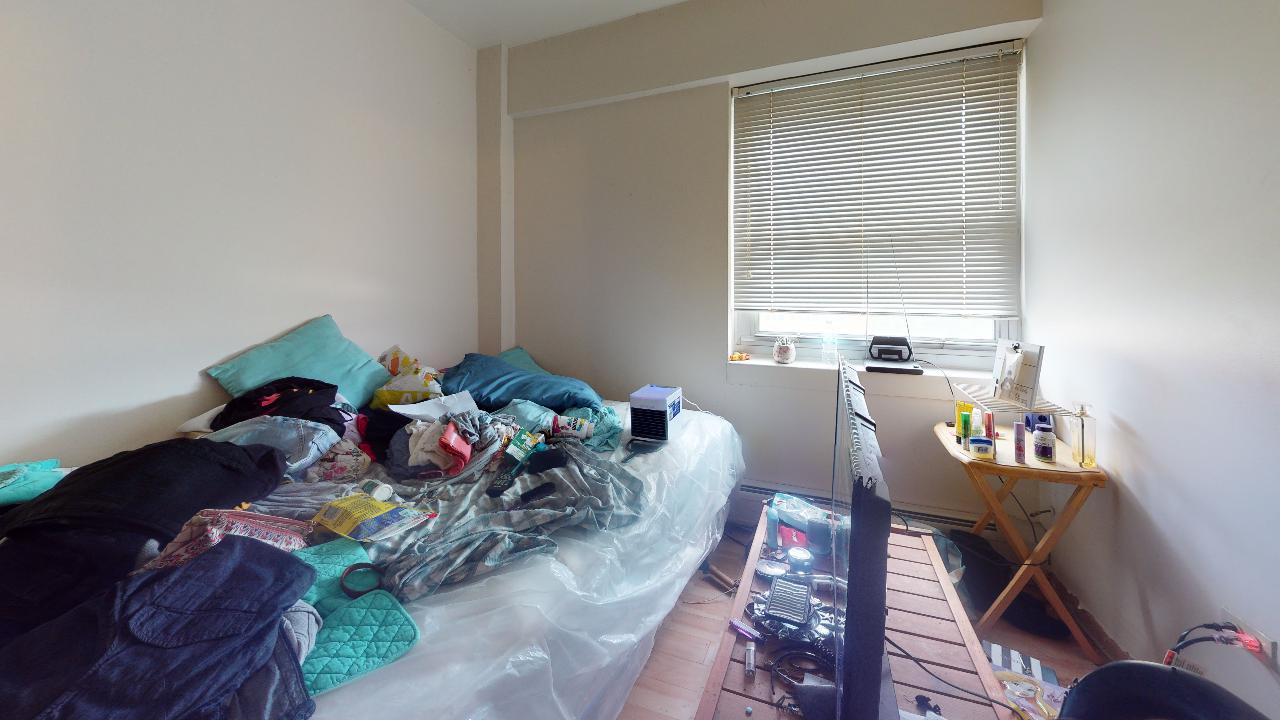 A bedroom with a bed , desk , television and window.