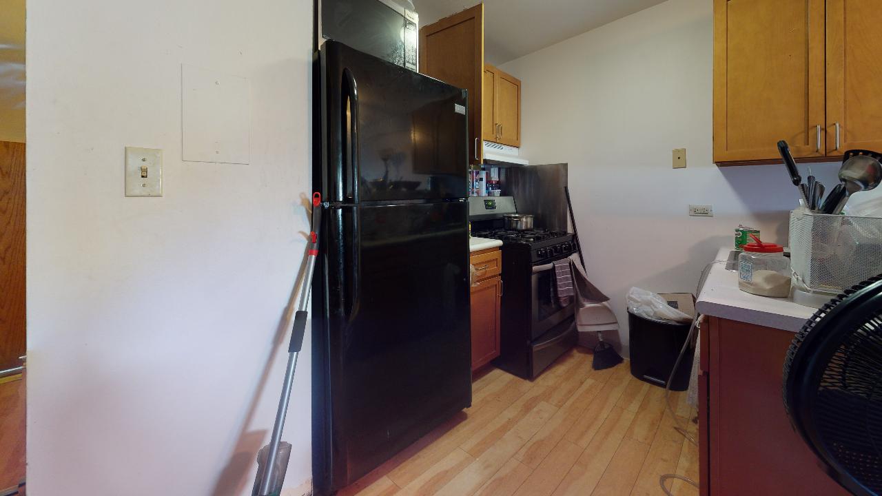 A kitchen with a black refrigerator , stove , washer and dryer.
