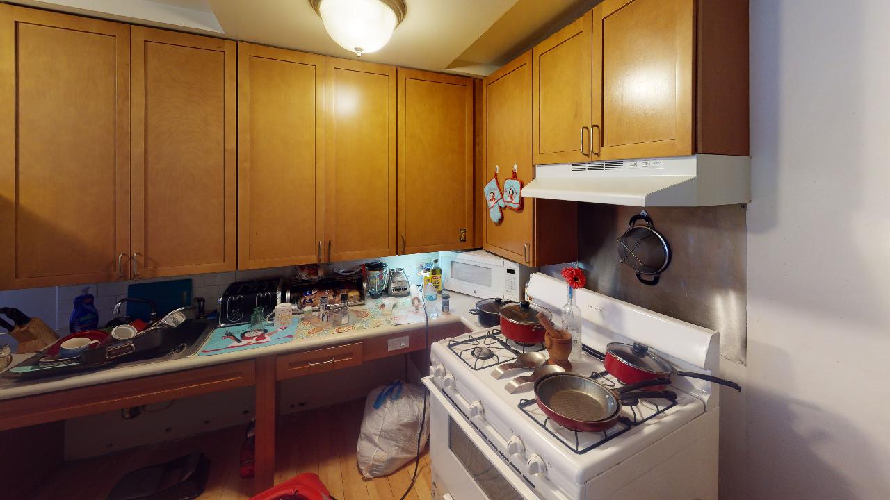 A kitchen with wooden cabinets , a stove , and a table.