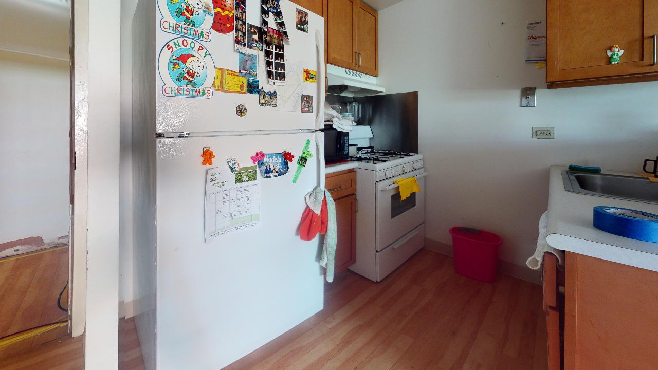 A kitchen with a refrigerator , stove , sink and cabinets.