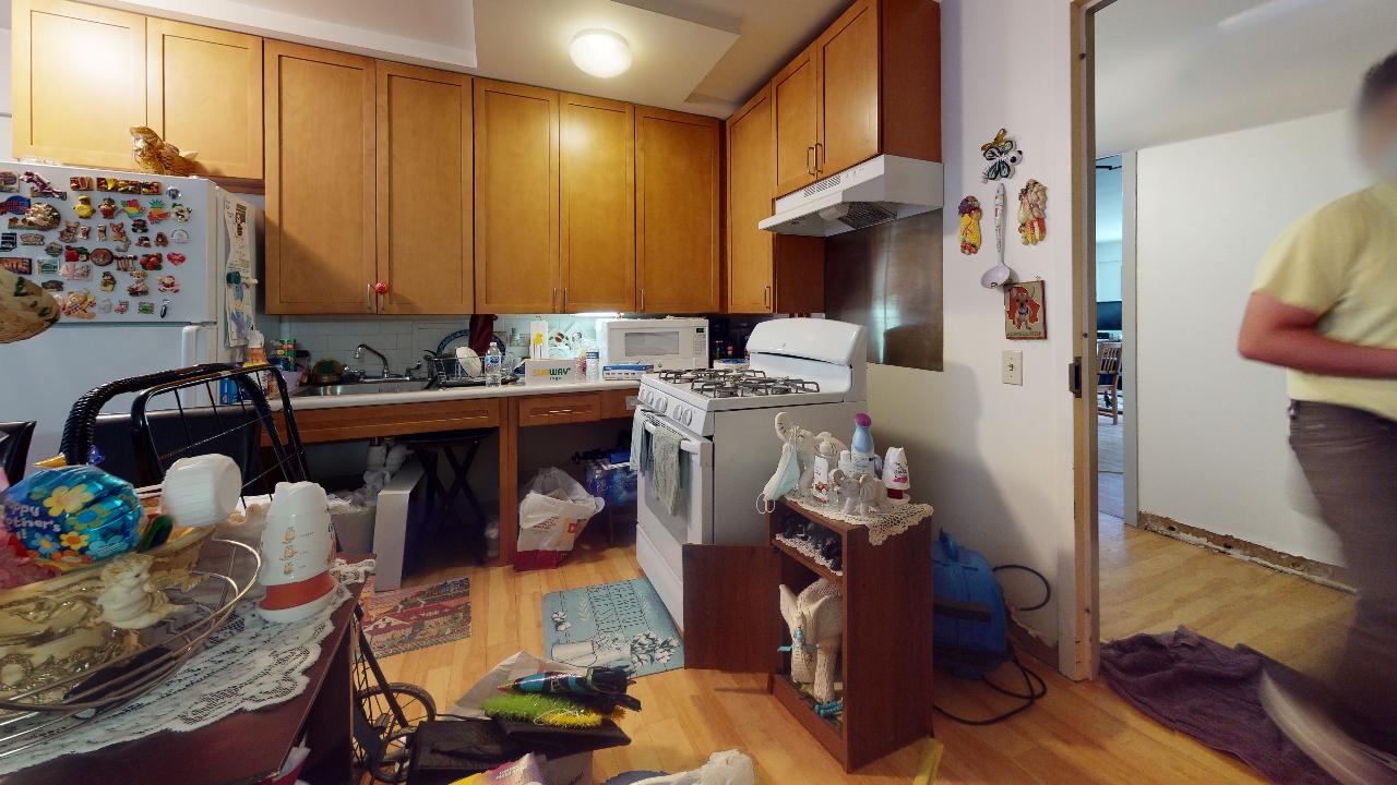 A kitchen with wooden cabinets , a stove , a refrigerator and a sink.