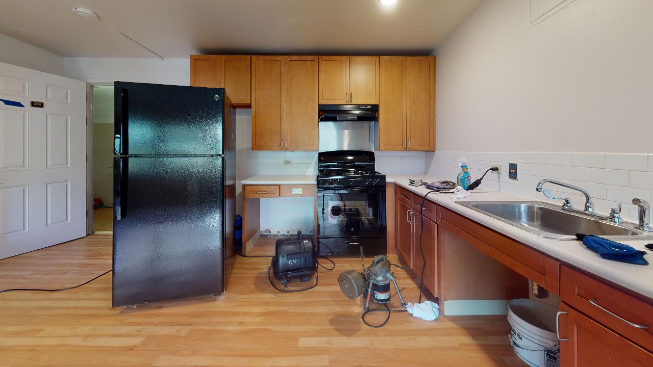 A kitchen with a black refrigerator , stove , sink and cabinets.