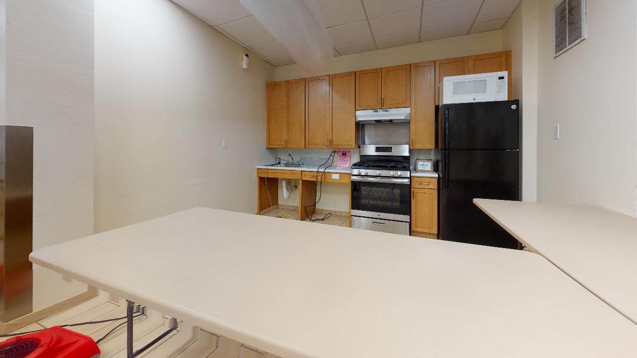 A kitchen with a table , refrigerator , stove and microwave.