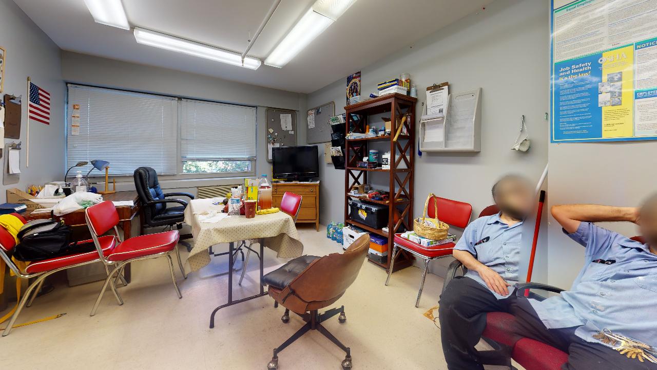 A group of people are sitting in a room with a table and chairs.