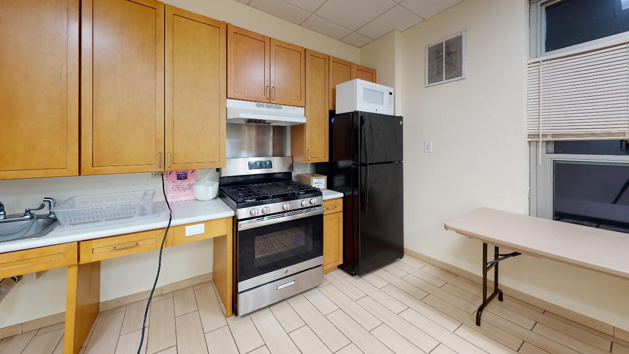 A kitchen with a stove , refrigerator , microwave , sink and table.