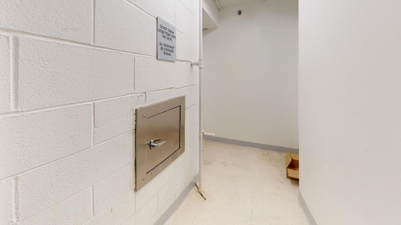 A hallway with a brick wall and a metal door.