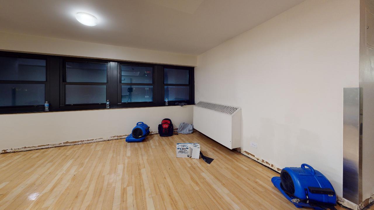 An empty room with a wooden floor and a lot of windows.