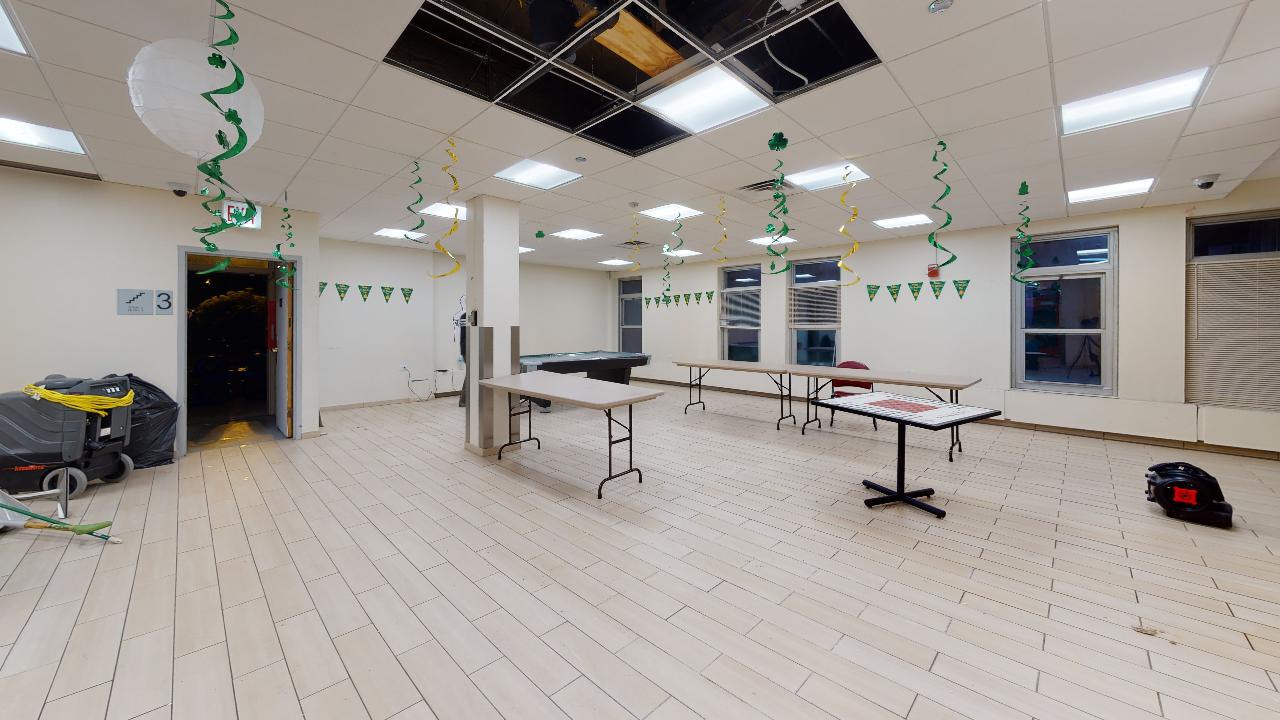 A large empty room with tables and balloons hanging from the ceiling.