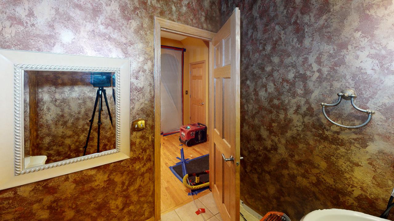 A bathroom with a sink , mirror , and door.