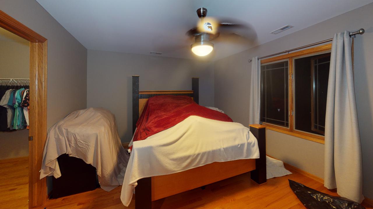 A bedroom with a bed and a ceiling fan.