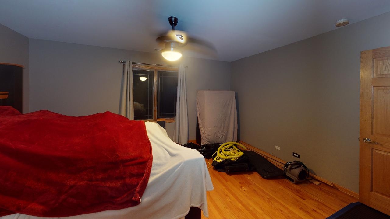 A bedroom with a bed and a ceiling fan.