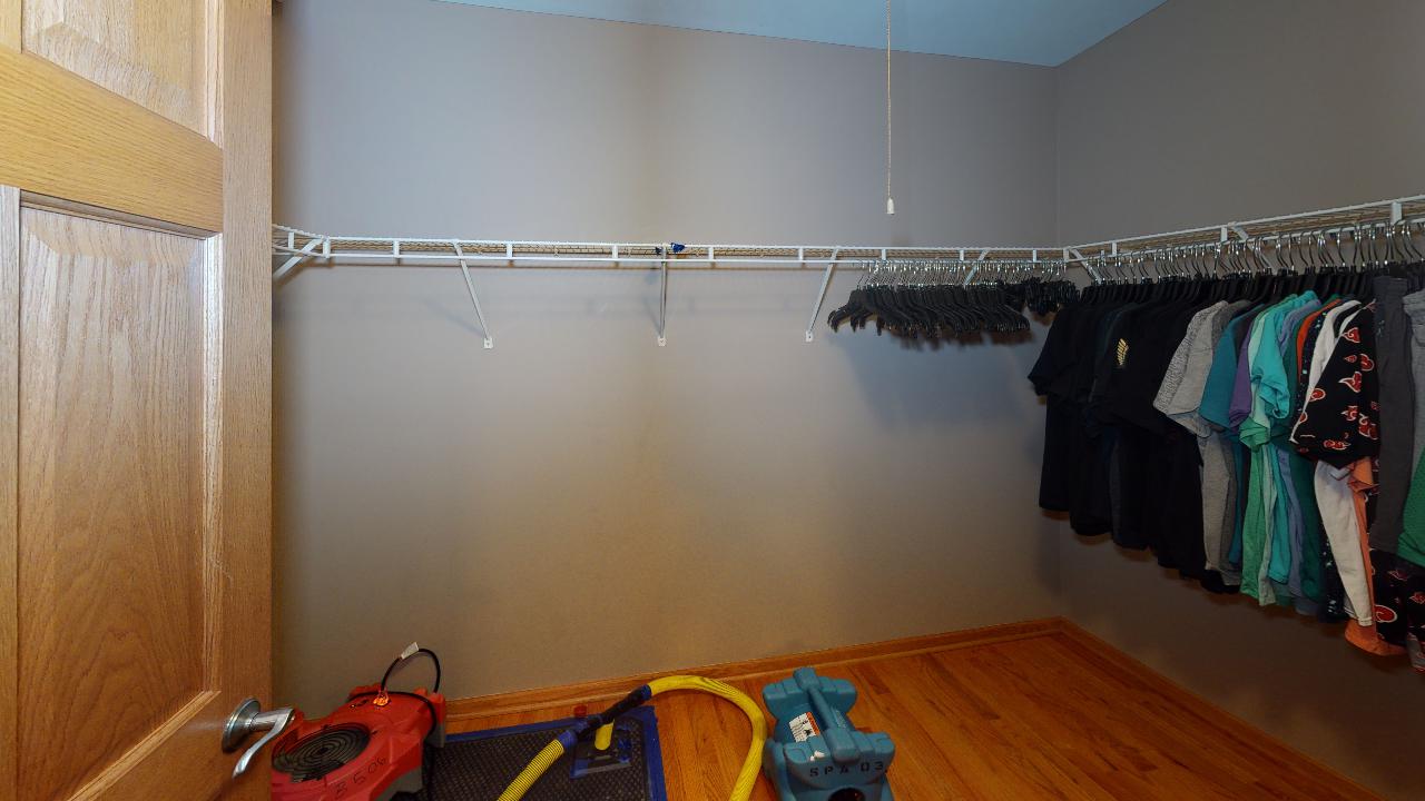 A walk in closet filled with clothes and a vacuum cleaner.