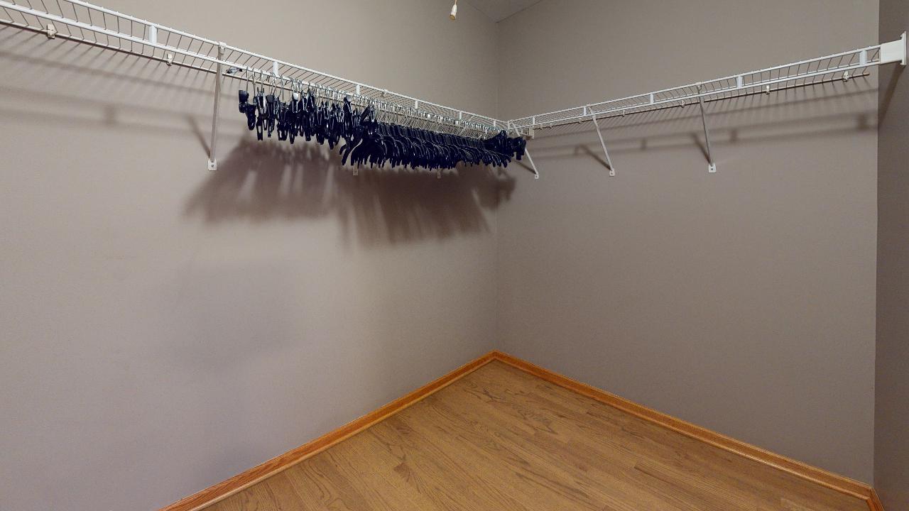 A walk in closet with a lot of clothes hanging on the racks.