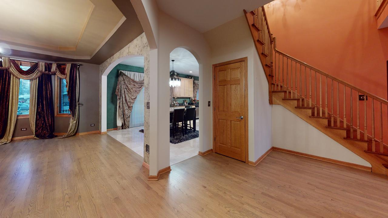 A living room with hardwood floors and stairs in a house.