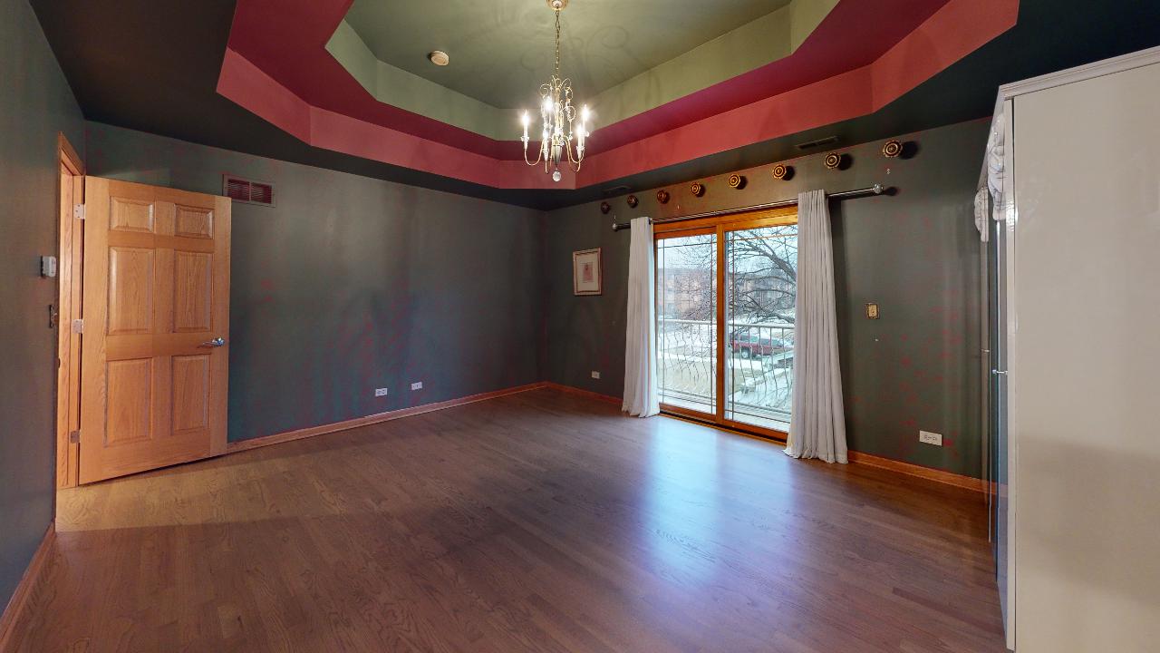 A large empty room with hardwood floors and a chandelier.
