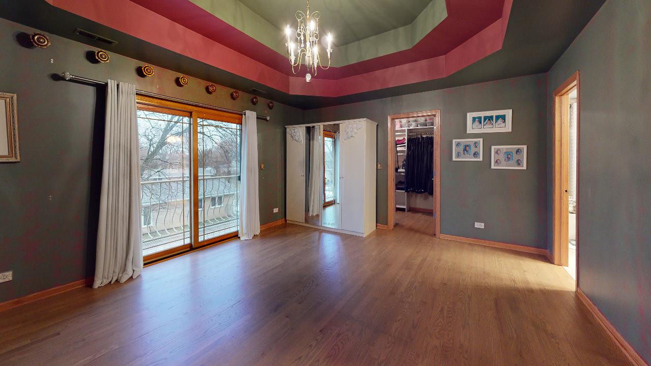 A large empty room with hardwood floors and a chandelier.