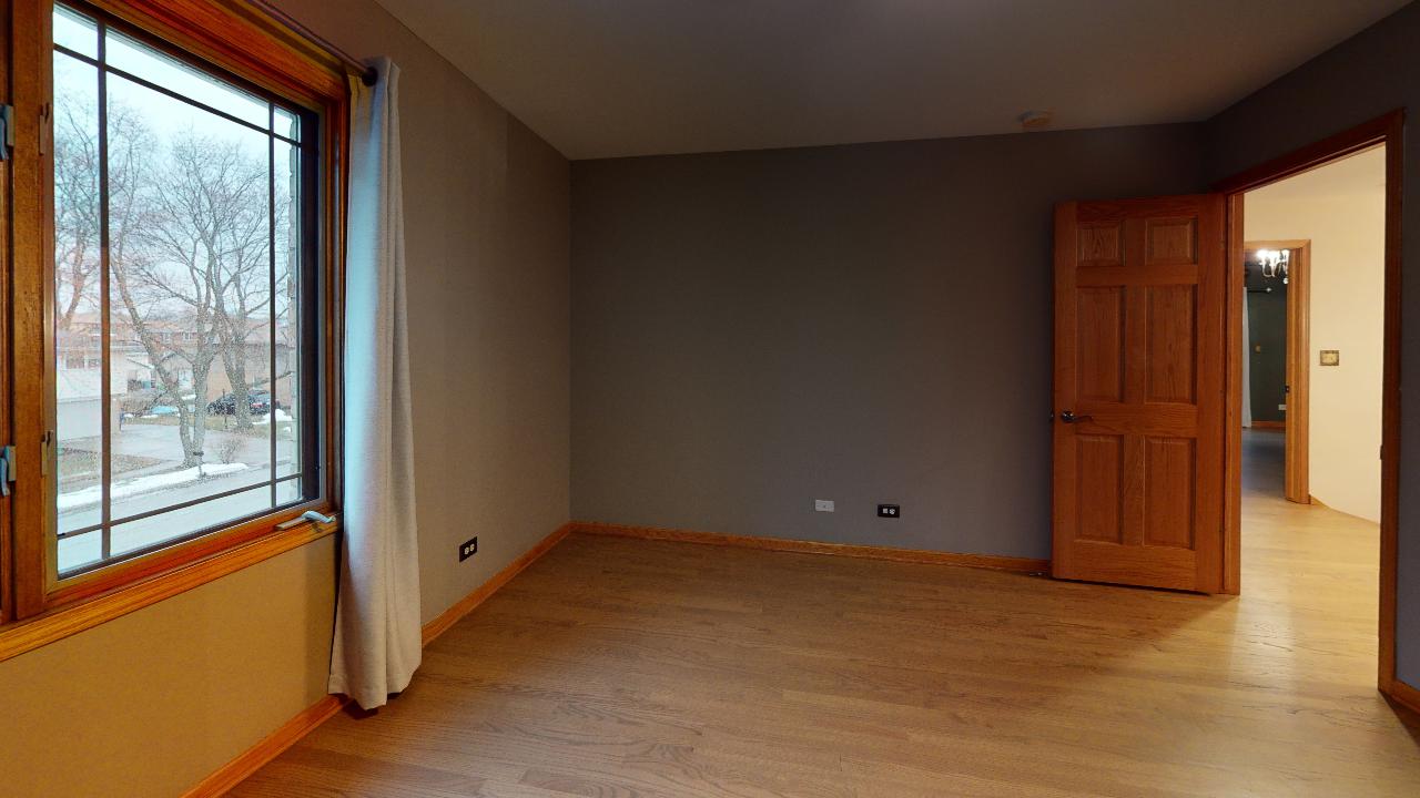 An empty room with hardwood floors and a large window.