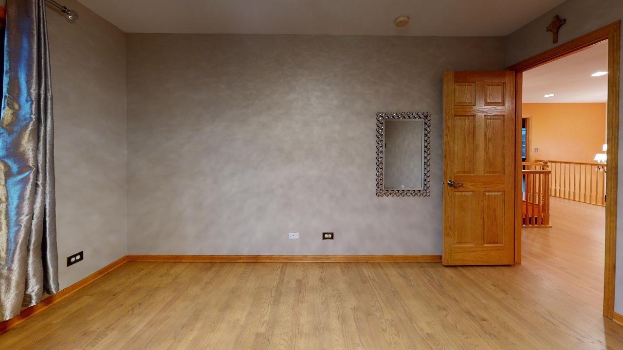 An empty room with a wooden floor and a mirror on the wall.