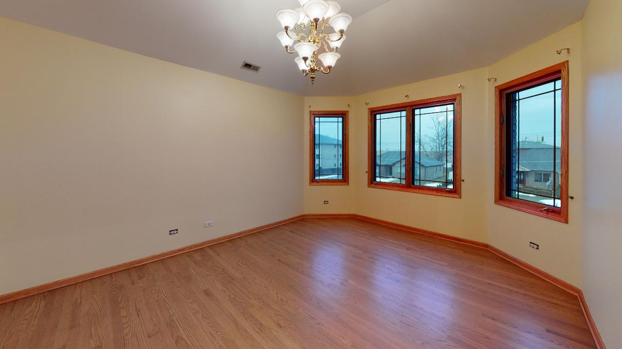 A large empty room with hardwood floors and a chandelier.