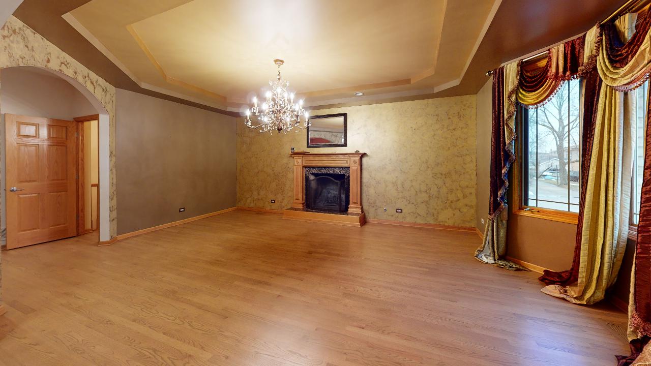 An empty living room with a fireplace and a chandelier.
