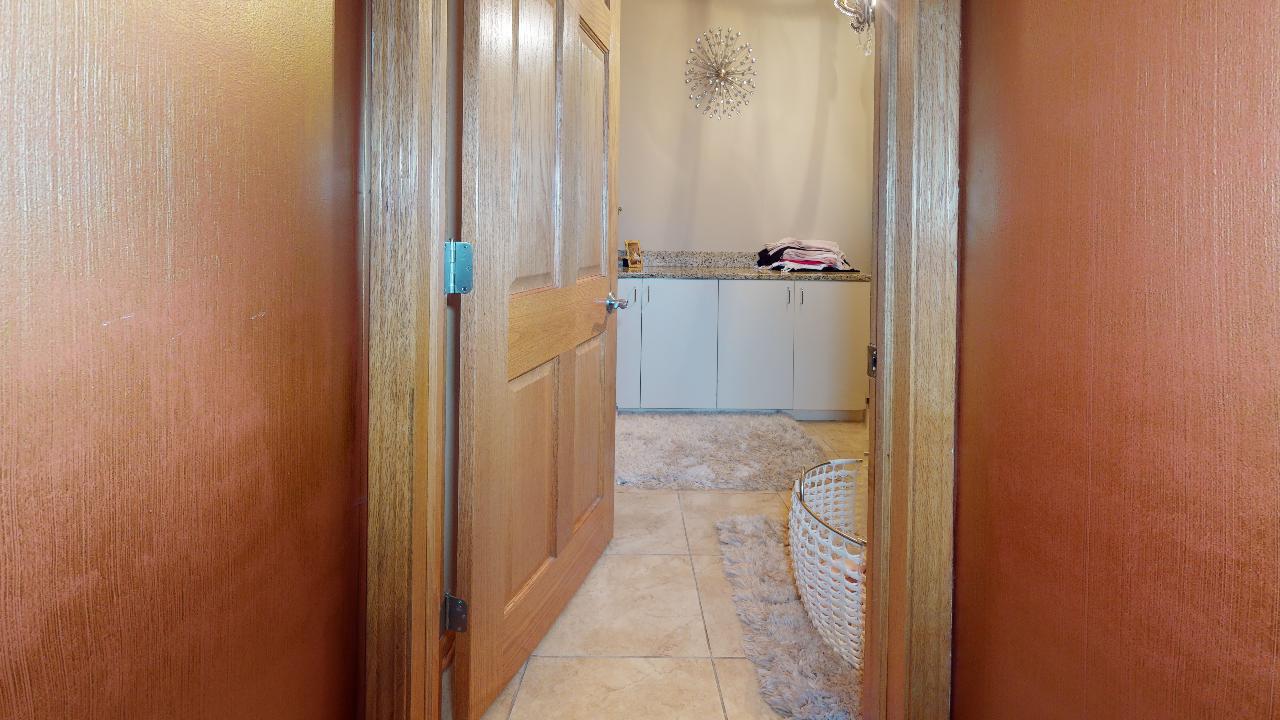 A hallway with a wooden door leading to a bathroom.