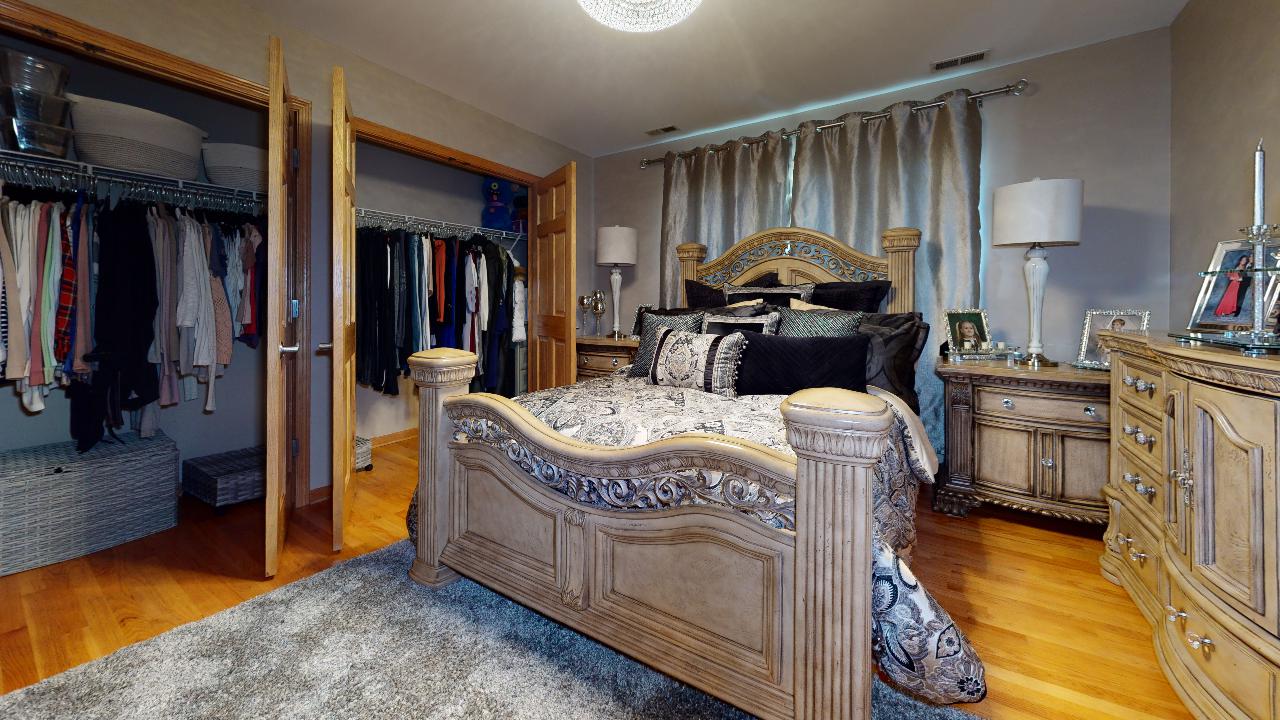 A bedroom with a large bed , dresser , nightstand and walk in closet.
