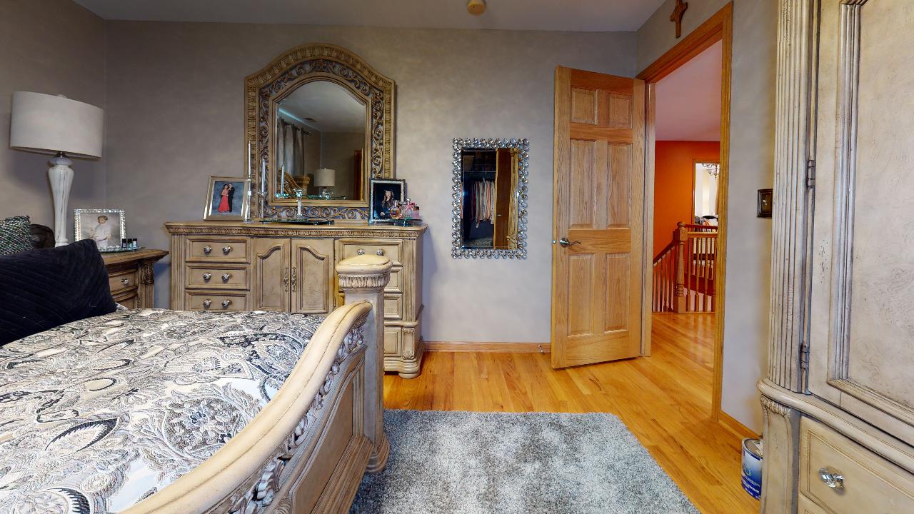 A bedroom with a bed , dresser , mirror and rug.