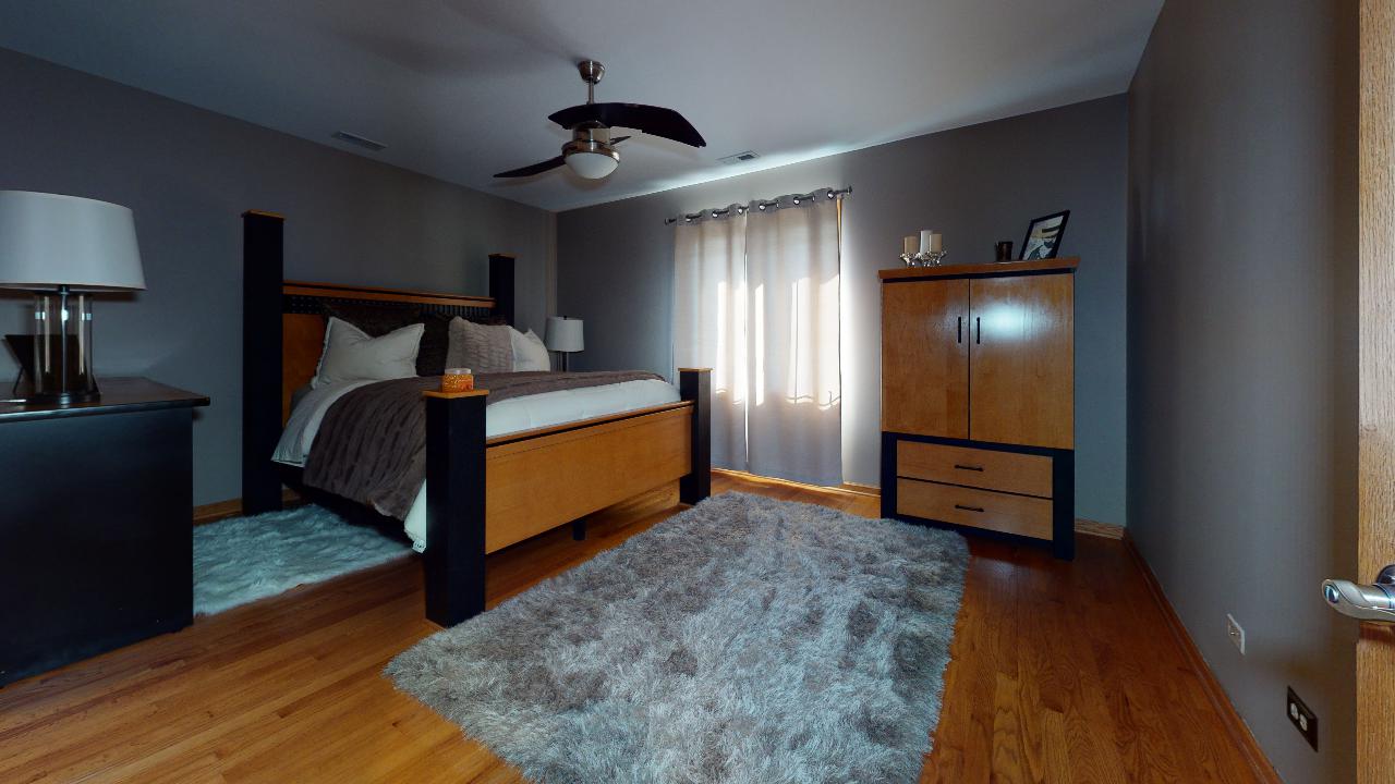 A bedroom with a bed , nightstand , rug and ceiling fan.