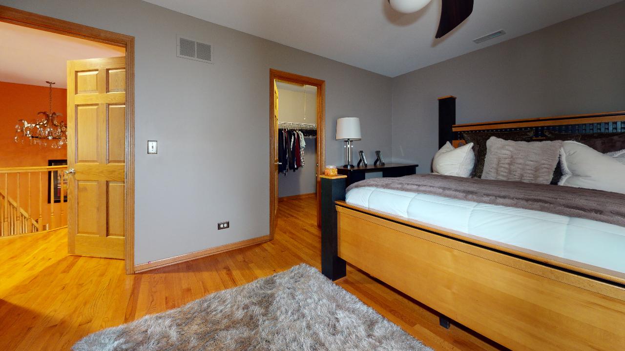 A bedroom with a large bed and a rug on the floor.