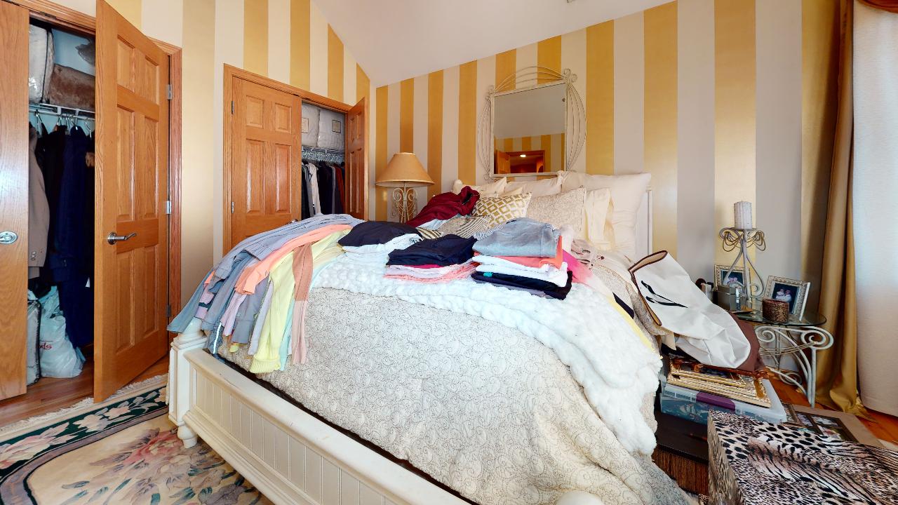 A bedroom with a bed , closet and striped walls.